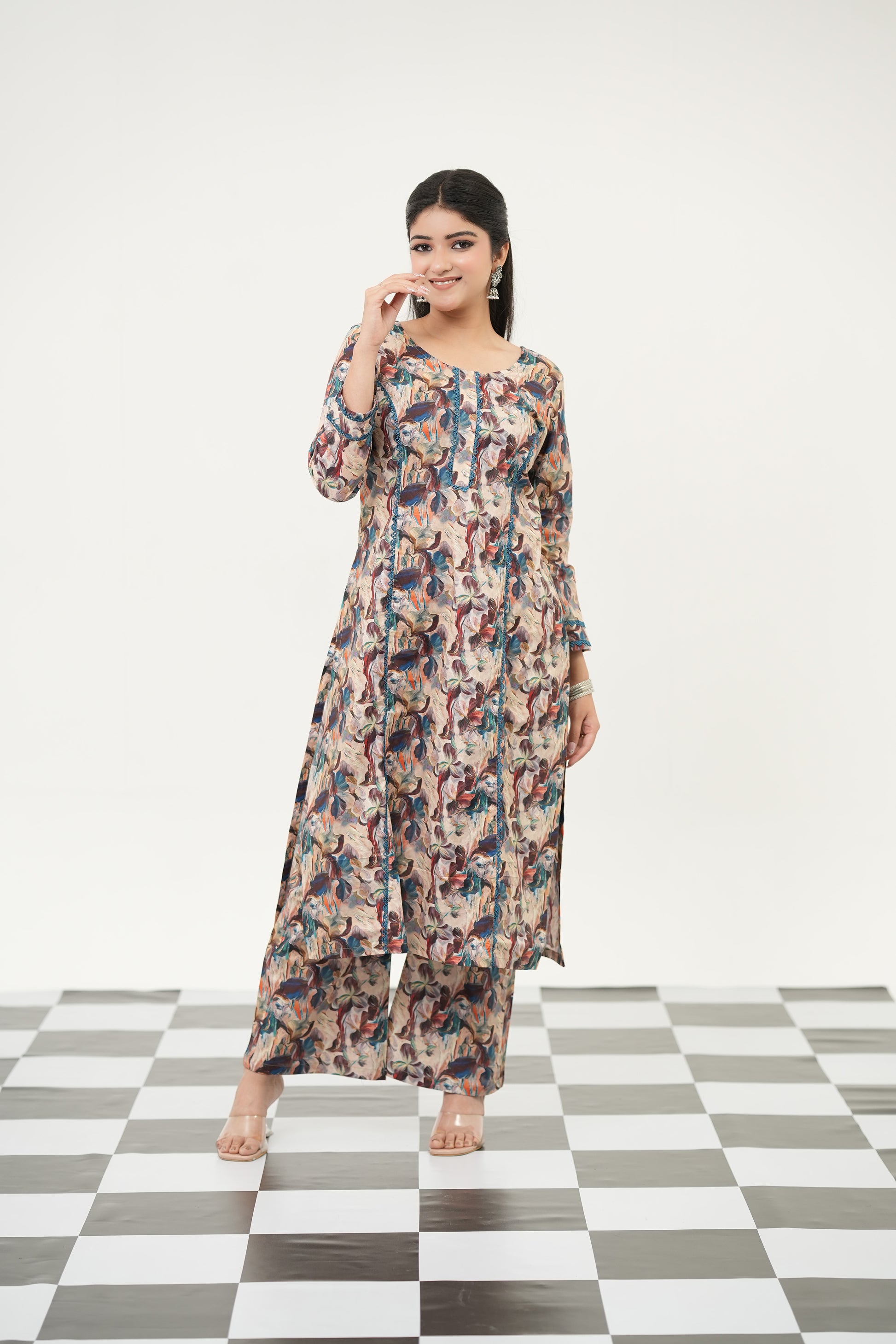 A woman standing on a checkered floor wearing a Cotton cambric abstract digital print kurta set with lacework accents and matching pants.