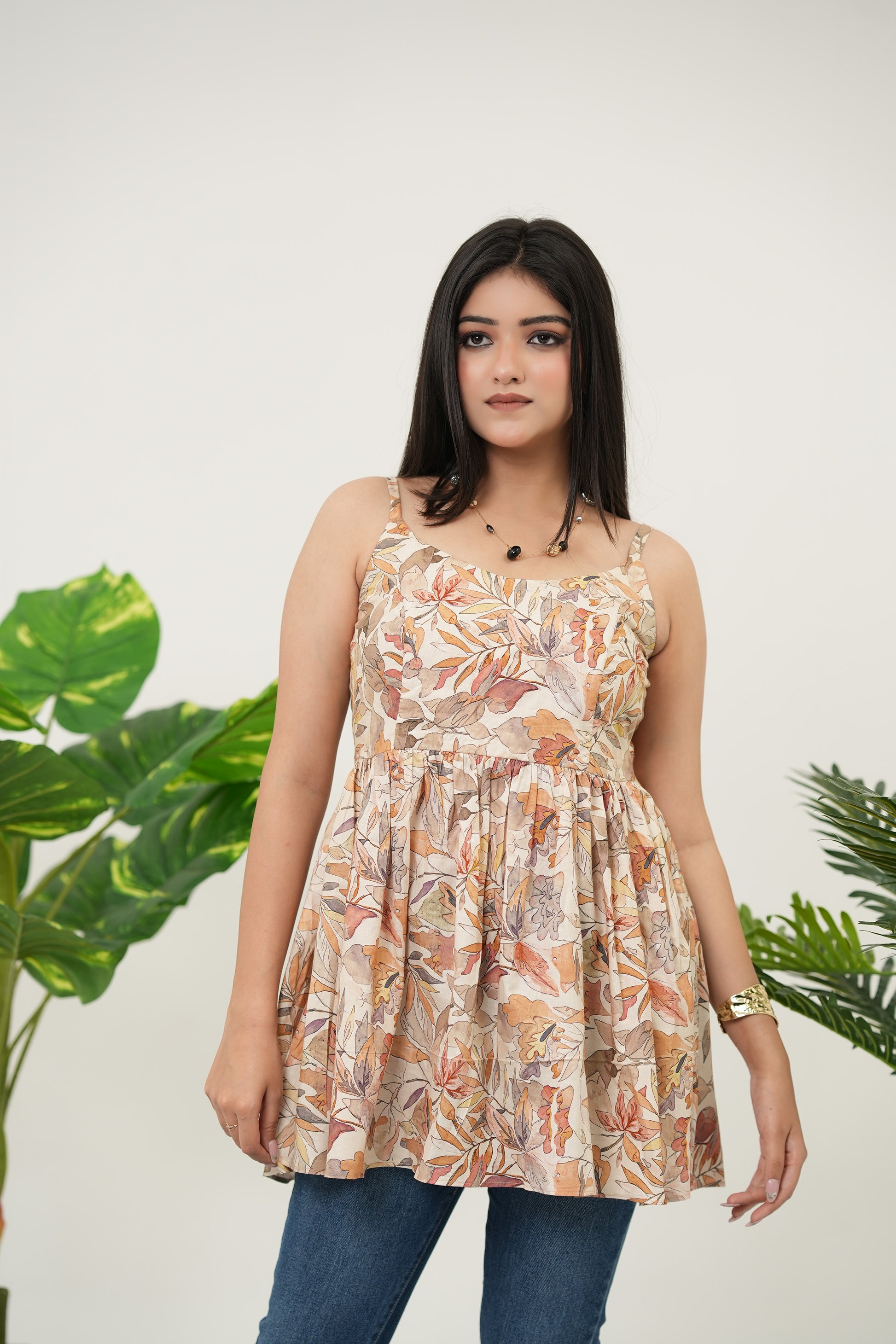 Model wearing Autumn Whispers Sleeveless Top, front-facing standing pose, beige cotton cambric, gathered silhouette, and soft digital autumnal leaf print - Simroz.
