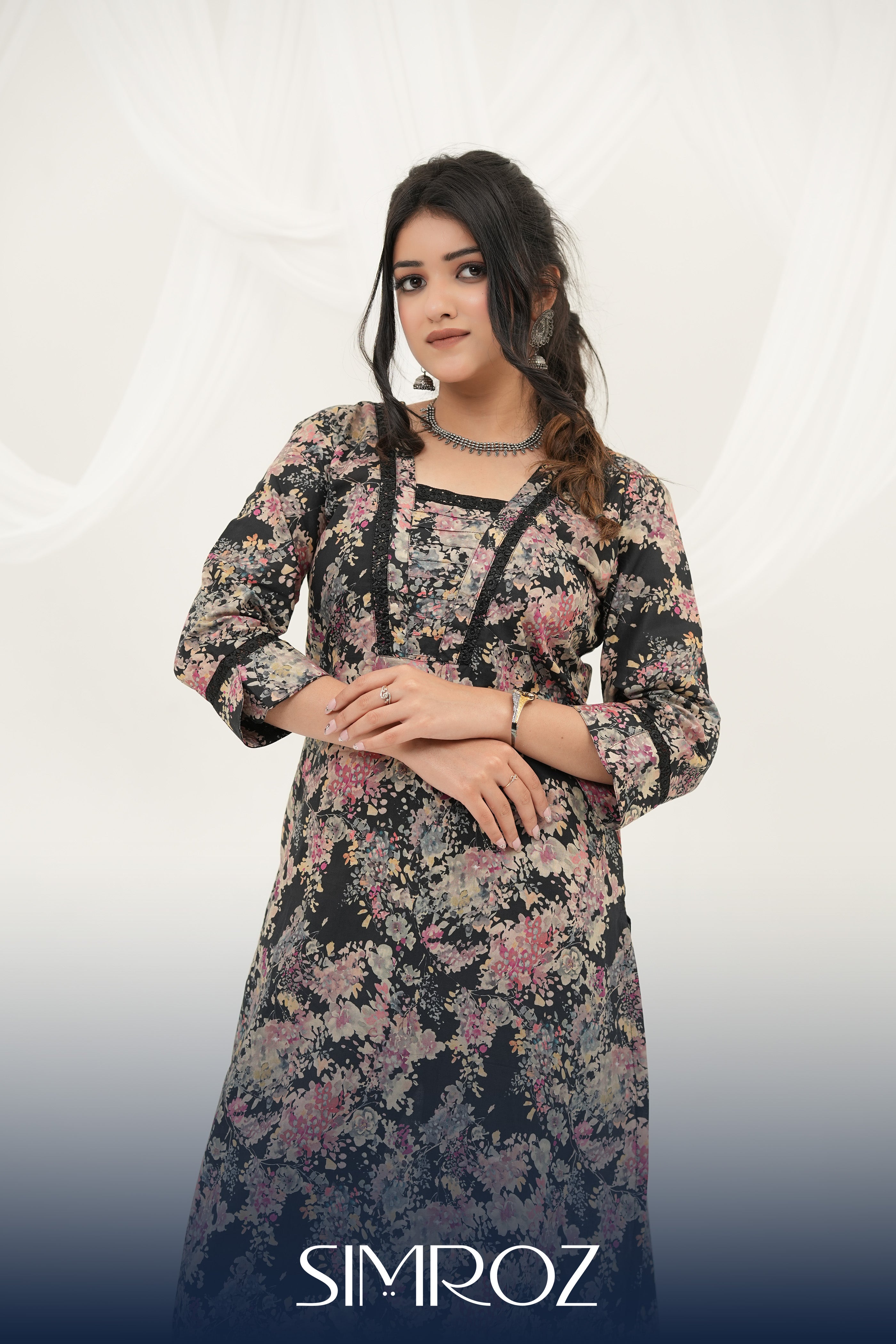 A woman posing in a Twilight Bloom black printed kurta set with vibrant floral digital print and lace detailing by SIMROZ.