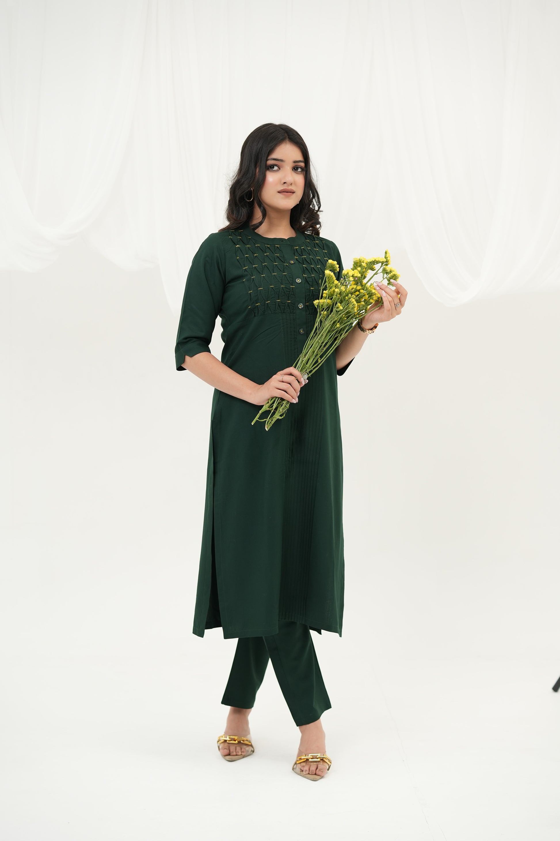 A woman standing against a white background, wearing a SIMROZ Emerald Weave kurta set designed with artisanal woven texture, subtle yellow beads, and elegant straight-fit silhouette.