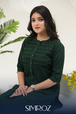 A woman sitting against a white background with Emerald Weave kurta set by SIMROZ featuring intricate woven yoke design, delicate beads handwork, and soft rayon viscose fabric.