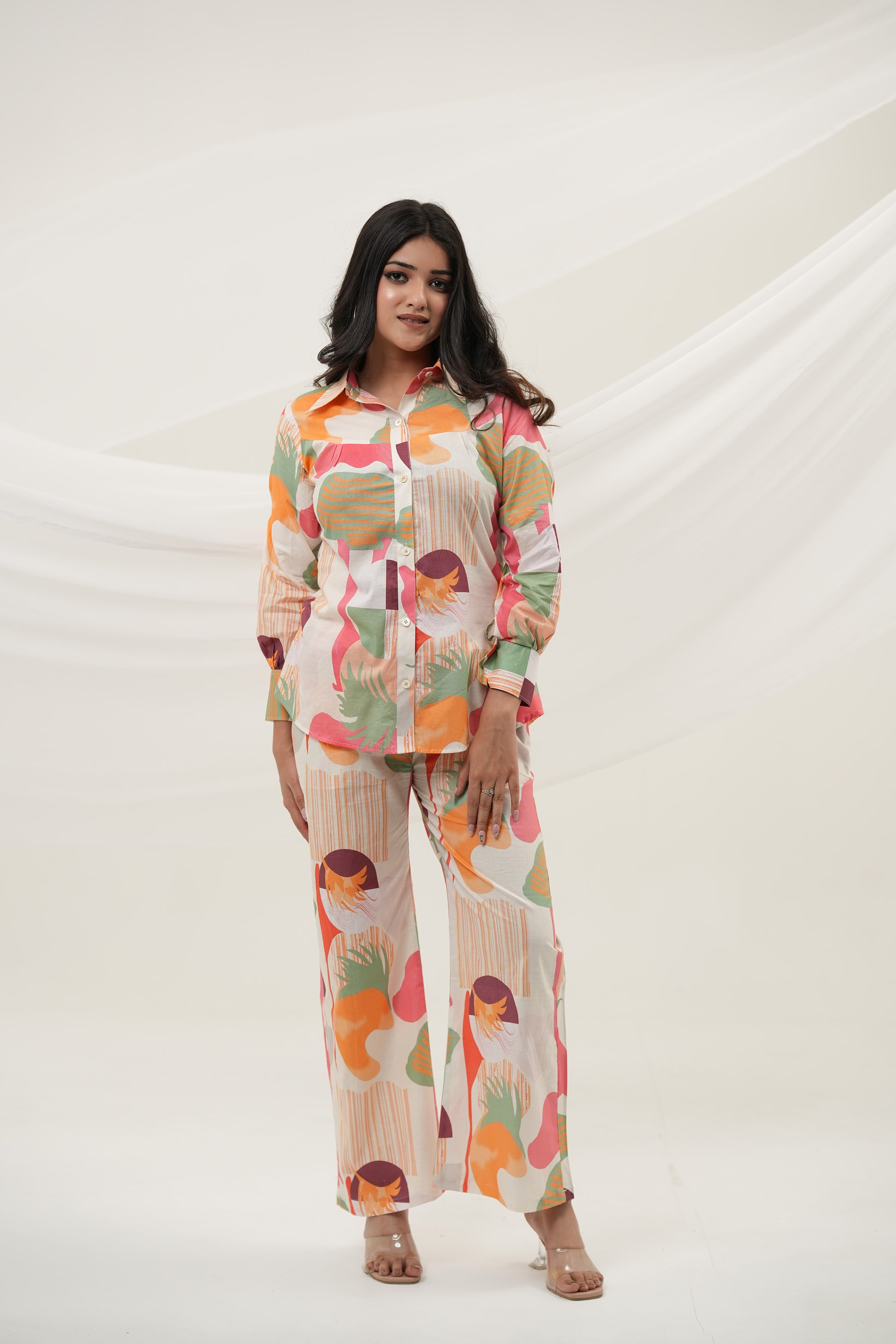 A woman is standing, posing, wearing a multicolored abstract print co-ord set consisting of a long-sleeved top and pants - Simroz.