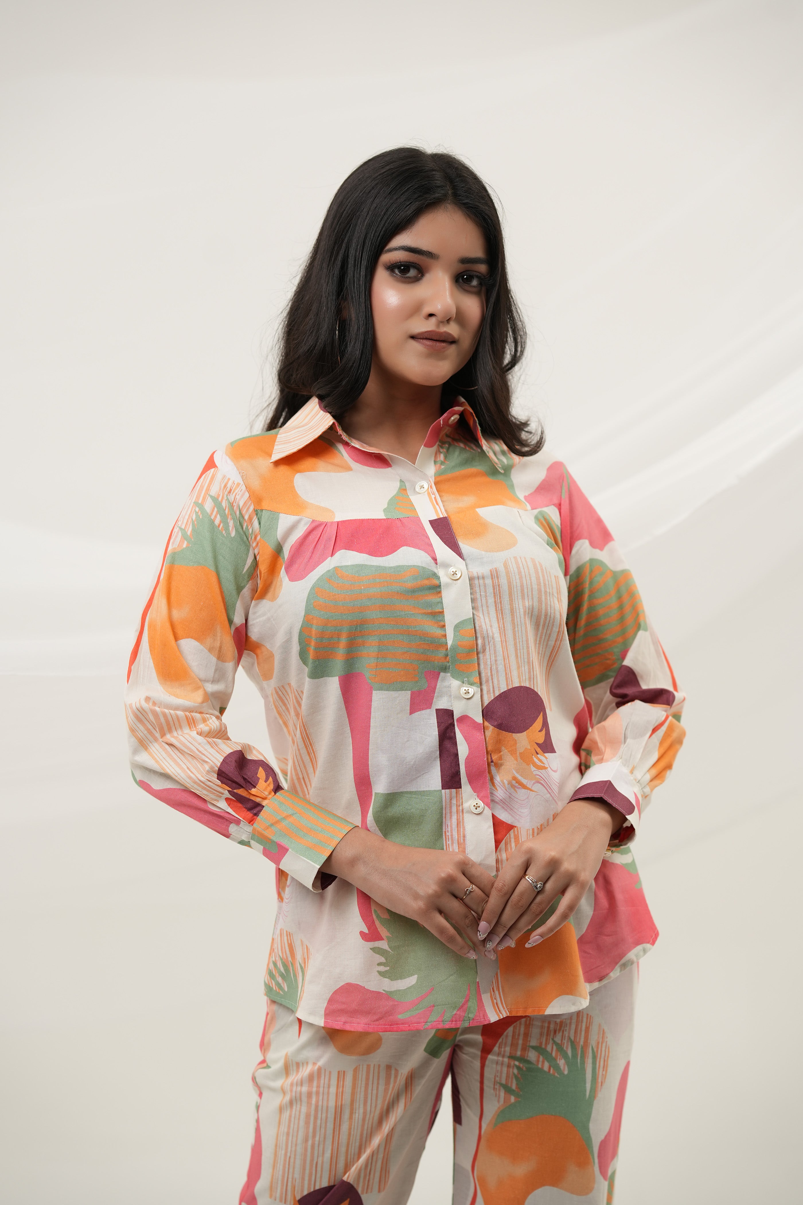A woman is standing, close-up, wearing a multicolored abstract print co-ord set consisting of a long-sleeved top and pants - Simroz.