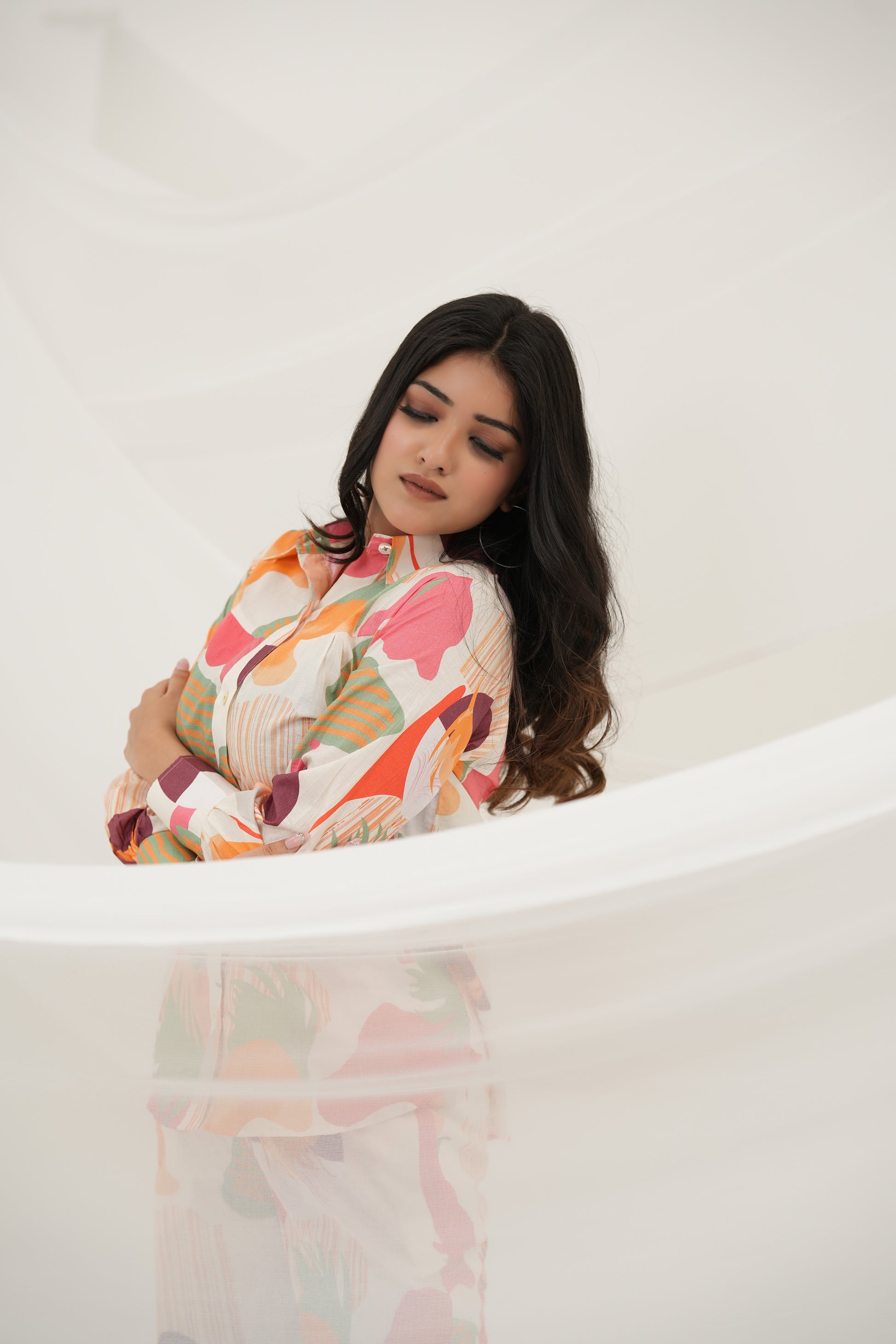 A woman is standing, wearing a multicolored abstract print co-ord set consisting of a long-sleeved top and pants, size view - Simroz.