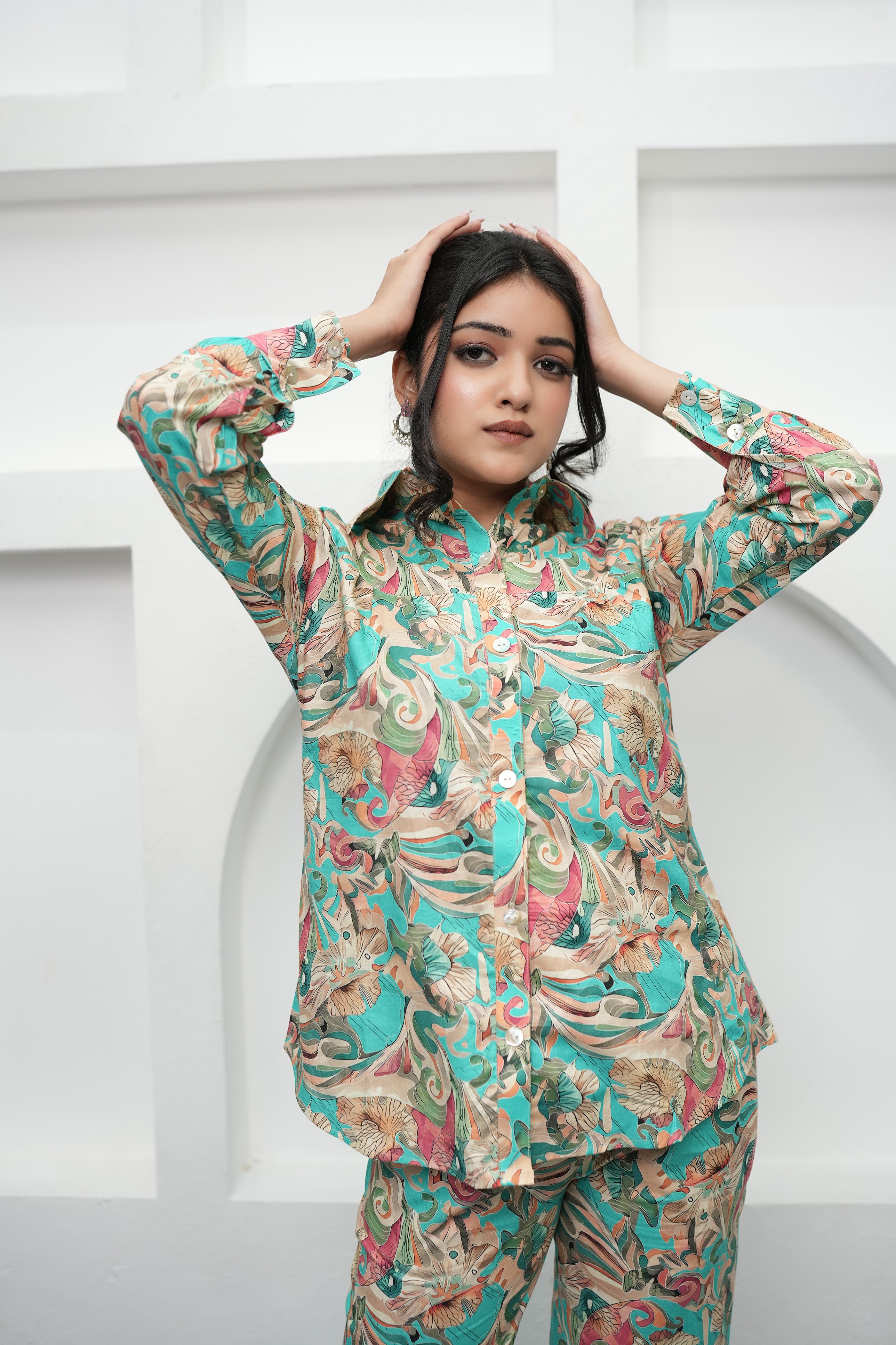 A woman is standing, hands over head, wearing a teal and beige printed co-ord set with a floral pattern - Simroz.