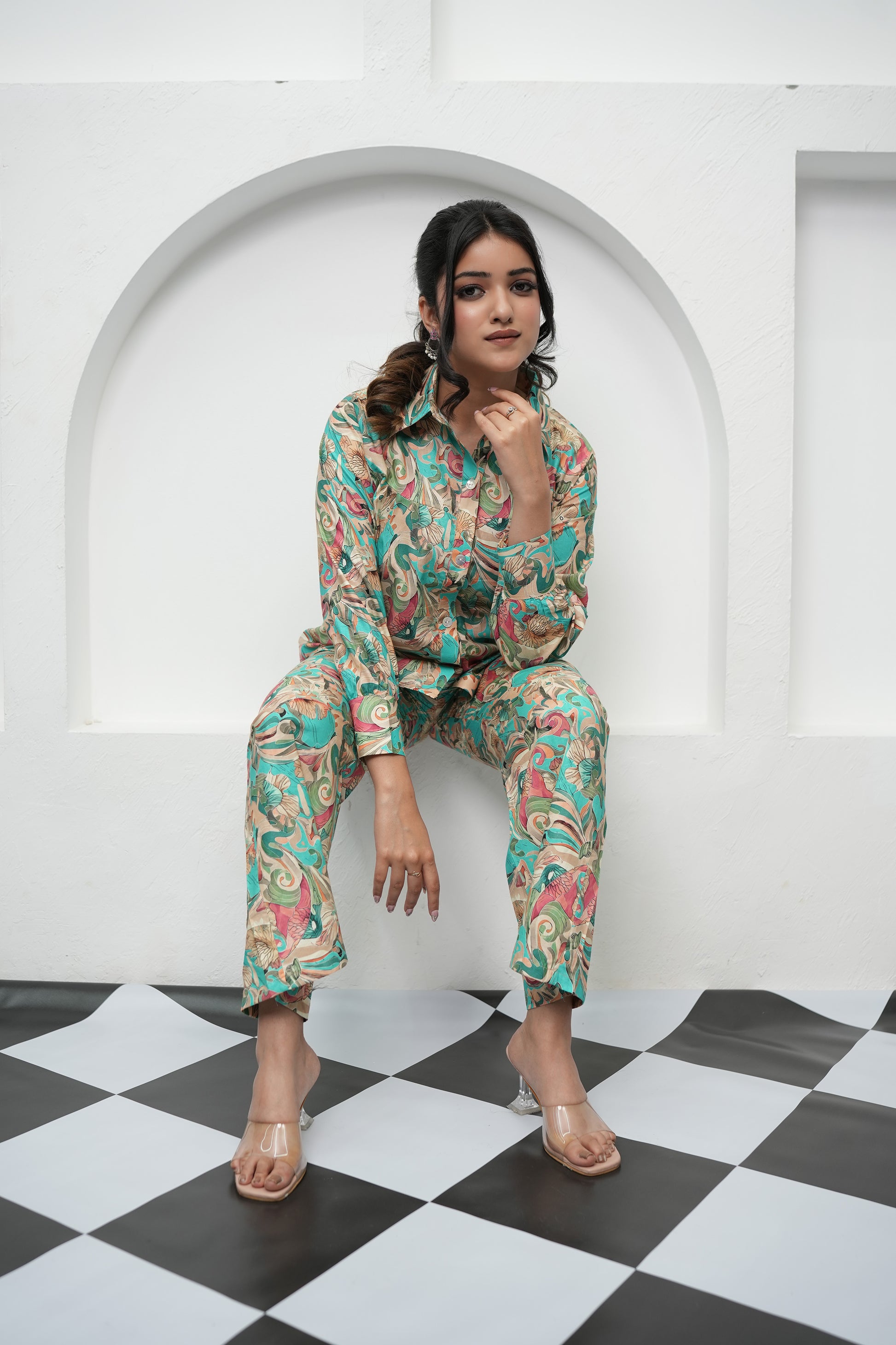 A woman is sitting, wearing a teal and beige printed co-ord set with a floral pattern - Simroz.