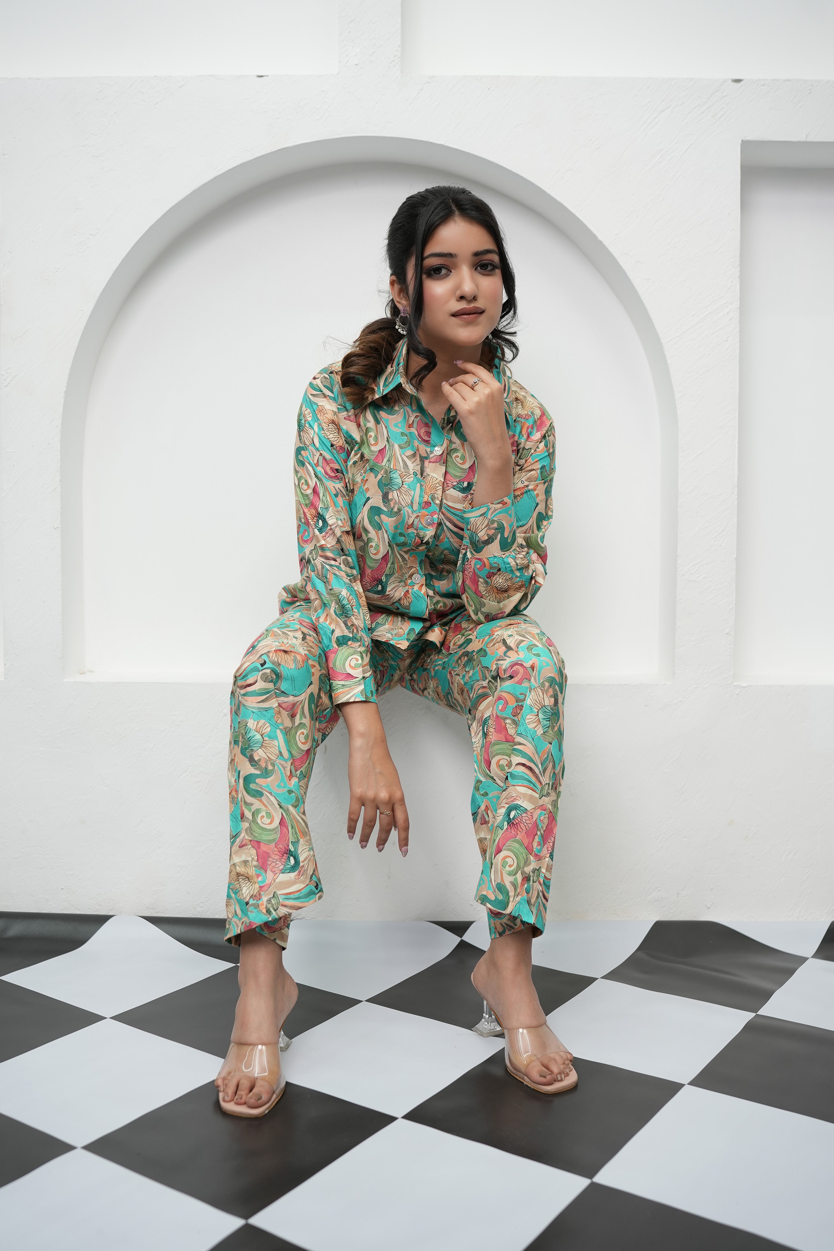 A woman is sitting, wearing a teal and beige printed co-ord set with a floral pattern - Simroz.