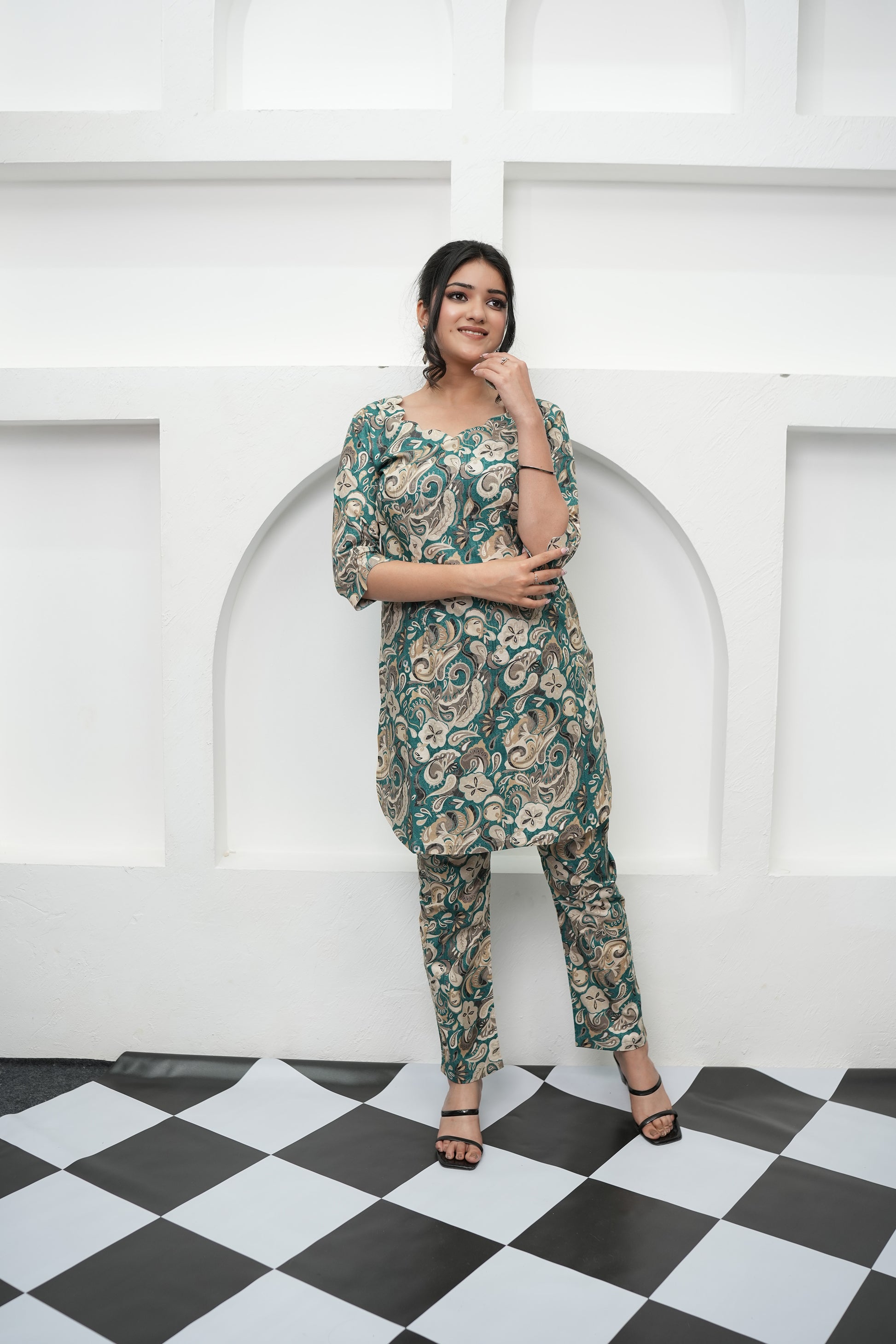 A woman standing in a tunic set with paisley print in deep teal, beige, and cream colors, paired with matching straight-leg pants - Simroz.