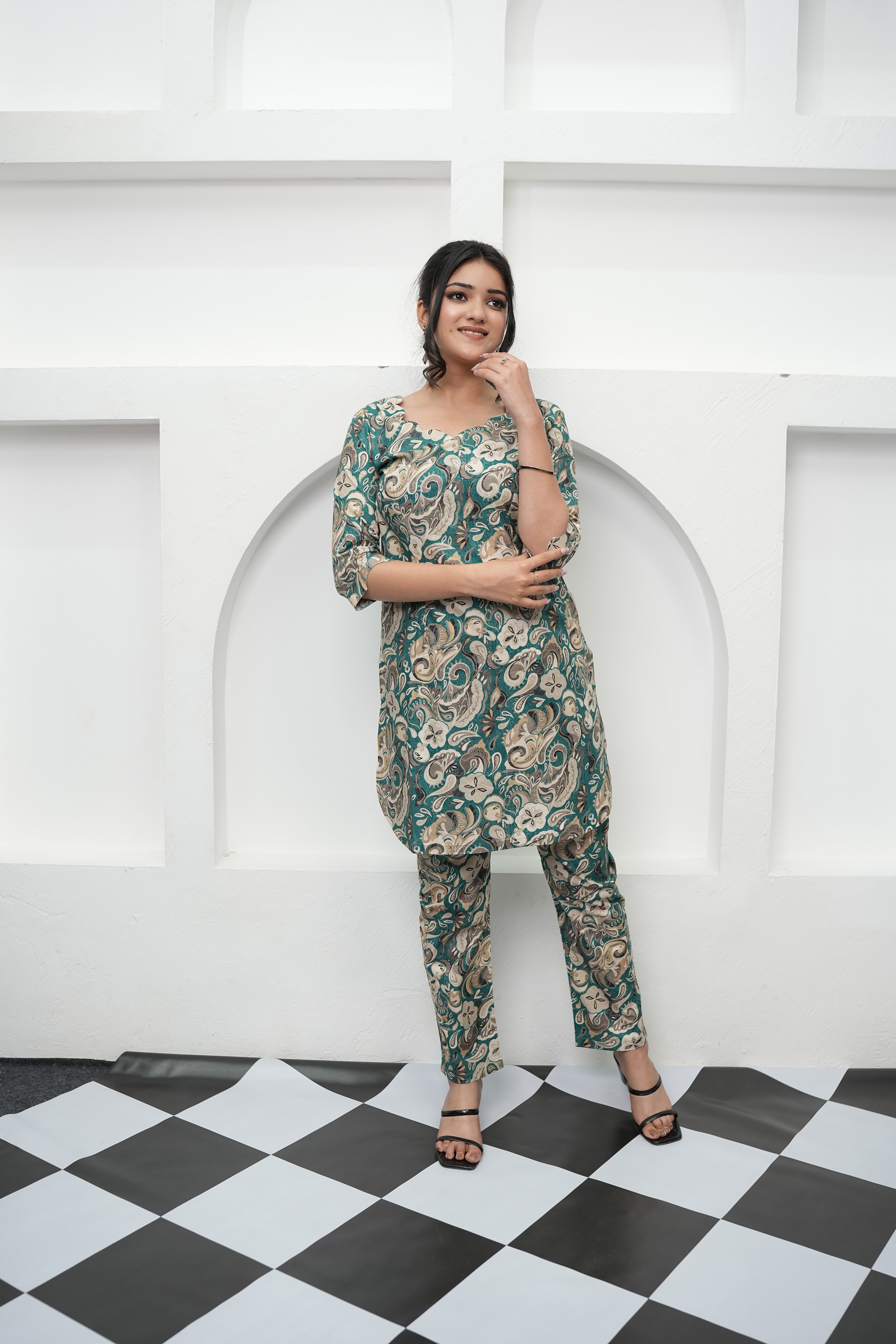 A woman standing in a tunic set with paisley print in deep teal, beige, and cream colors, paired with matching straight-leg pants - Simroz.