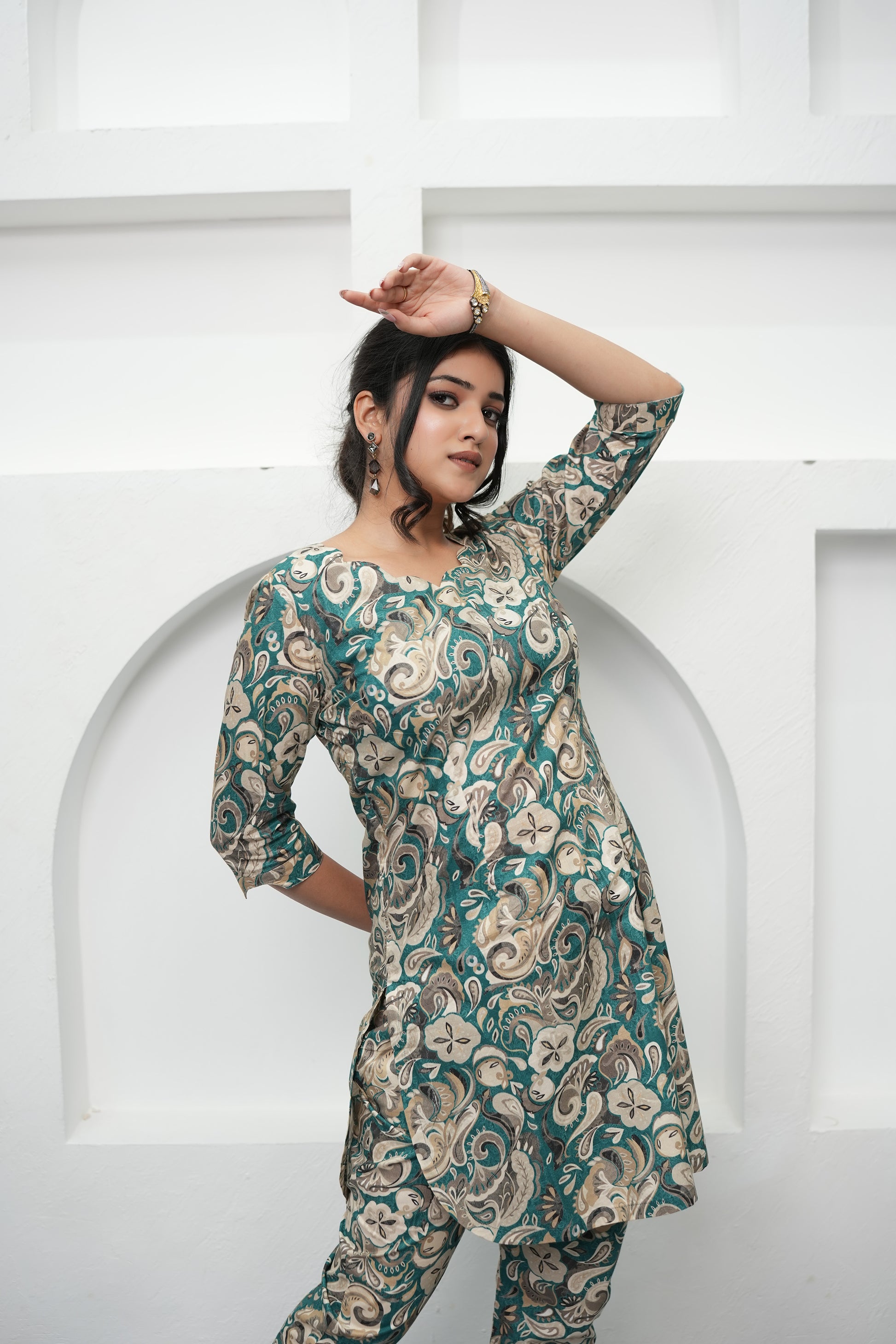 A woman wearing a paisley print tunic in deep teal, warm beige, and soft cream colors with three-quarter sleeves and a round neckline, front view - Simroz.