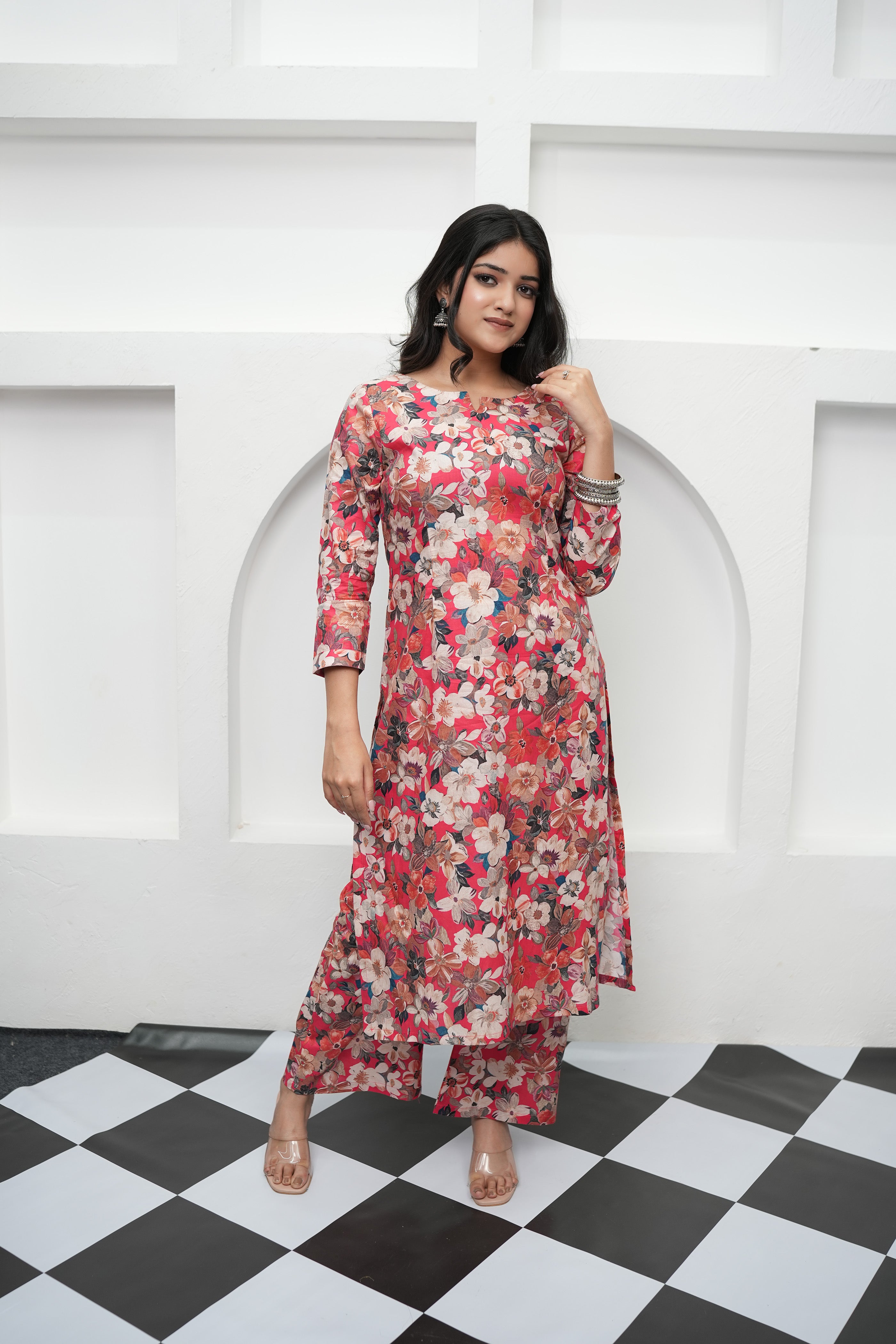 A woman standing in front of a white archway wearing a Scarlet Bloom kurta set by SIMROZ designed with lively multicolor floral patterns and soft cotton cambric.