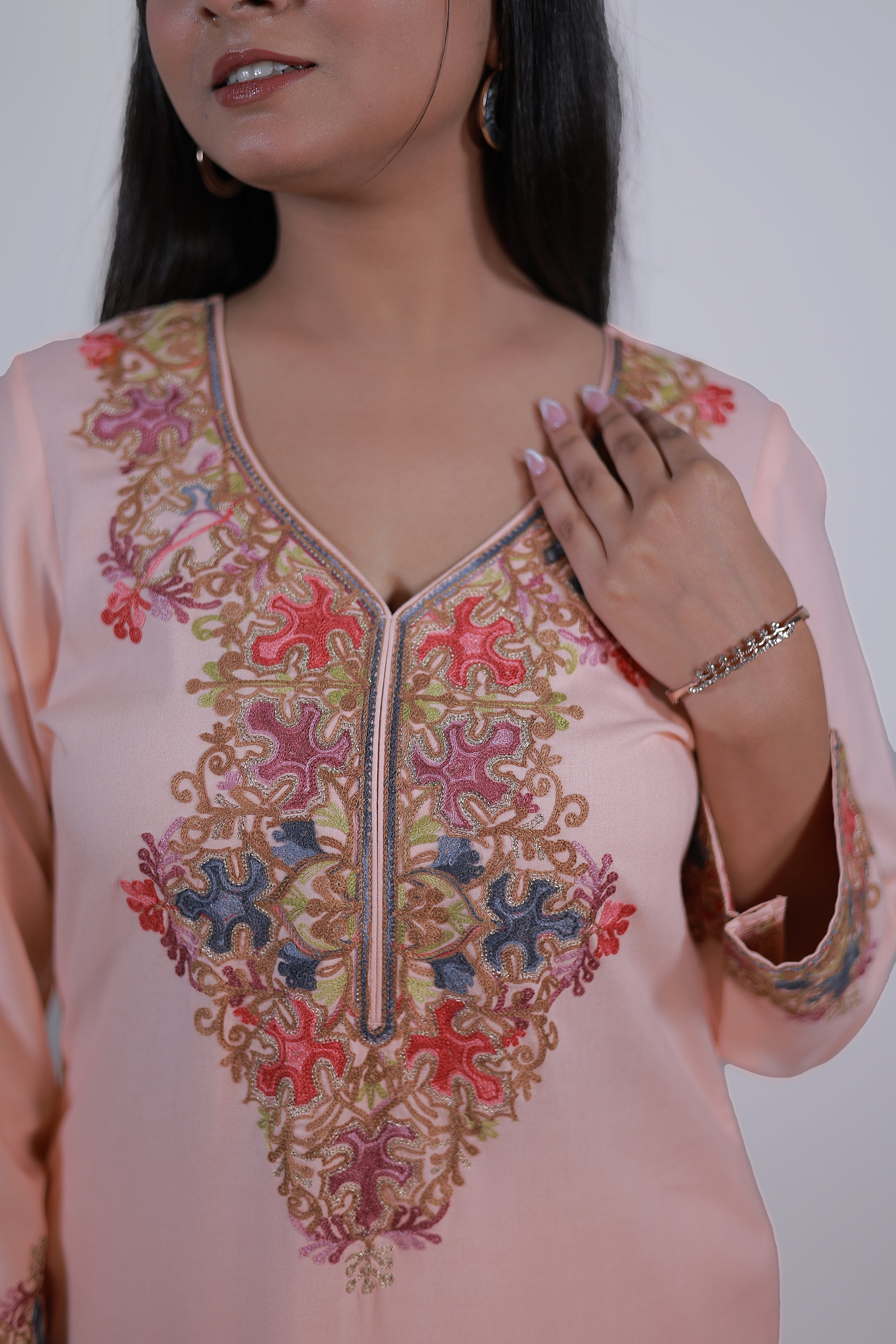 Close-up of peach orange Kashmiri embroidered Gul-e-Kashmir Kurta Set by Simroz with intricate detailing on neckline and sleeves