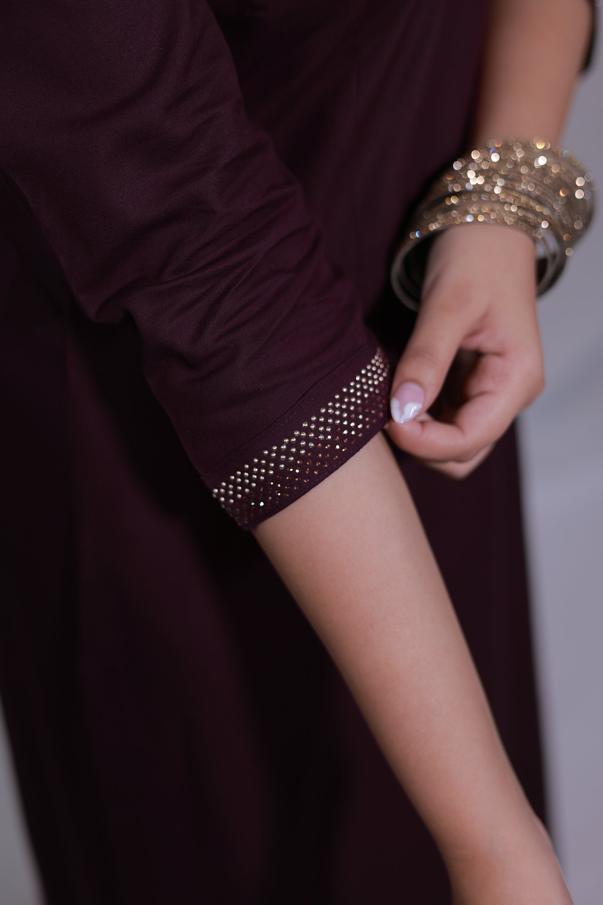 Close-up of a sleeve style, a model wearing a Surayya kurta set in wine color with Swarovski embellishments - Simroz.